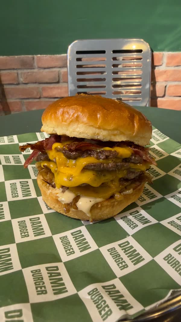Damalı Damn Burger kağıdı üstünde katlı cheddarlı smash burger